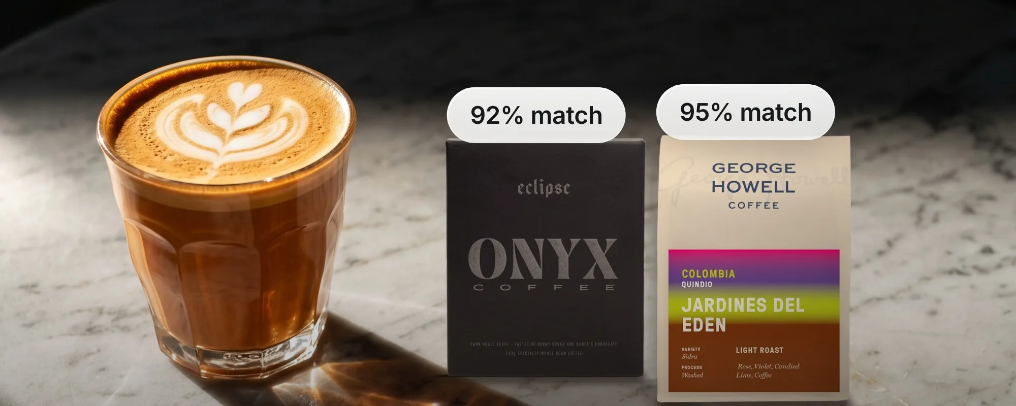 A latte on a marble table next to a box of Onyx Eclipse and a bag of George Howell Jardines del Edén, matched 92% and 95% to one subscriber's taste