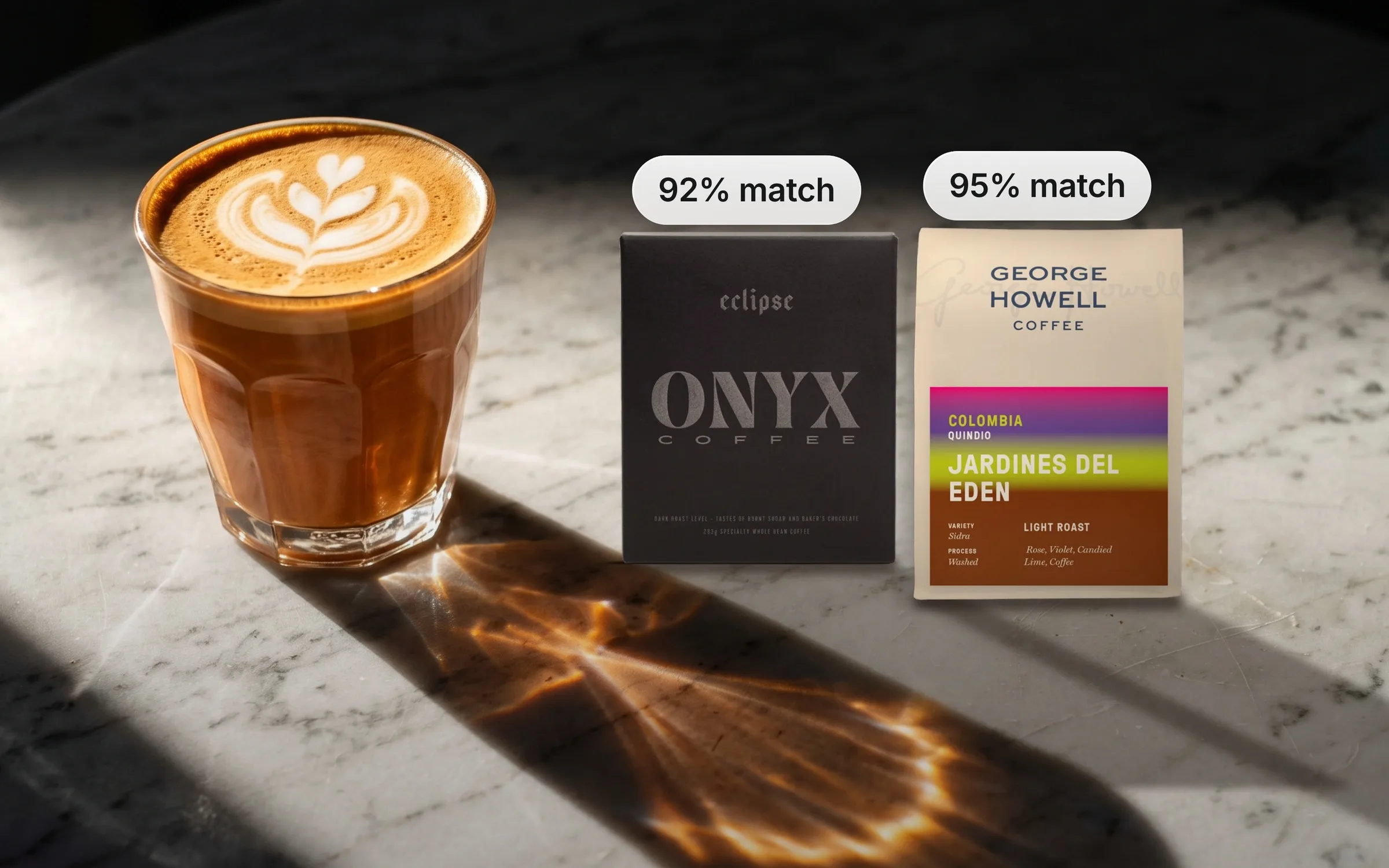 A latte on a marble table next to a box of Onyx Eclipse and a bag of George Howell Jardines del Edén, matched 92% and 95% to one subscriber's taste